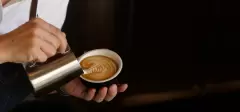 Barista przygotowuje kawę o bogatym składzie, zdobiąc ją spienionym mlekiem, aby pobudziła swym smakiem, aromatem.